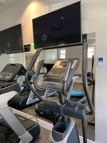 A gym with treadmills and a television mounted on the wall.