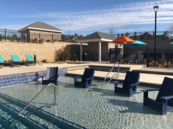 A pool with a metal fence and a small building in the background.