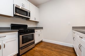 San Francisco apartment for rent - A kitchen with white cabinets and a black stove top oven.