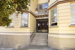 San Francisco apartment for rent - A yellow building with a black door and steps leading up to it.