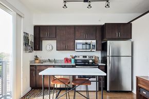 Minneapolis apartment for rent - a kitchen with stainless steel appliances and wooden cabinets and a white table with three chairs