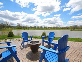 Verona apartment for rent - a patio with blue chairs and a fire pit overlooking a lake