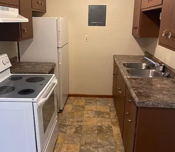 West Fargo apartment for rent - A kitchen with a white stove top oven and a white refrigerator.