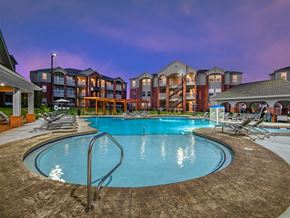 Bentonville apartment for rent - a swimming pool with chairs around it in front of an apartment building
