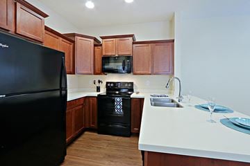 Glendale townhouse for rent - a kitchen with black appliances and wooden cabinets and white counter tops