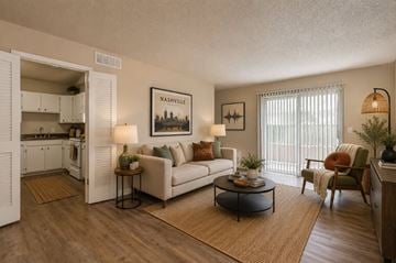 Nashville apartment for rent - A living room with a white couch, a coffee table, and a painting of Nashville on the wall.
