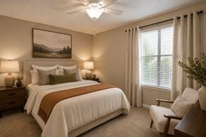 Nashville apartment for rent - A bedroom with a large bed, a painting on the wall, and a window with curtains.