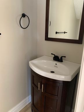 Smithfield apartment for rent - A bathroom sink with a brown cabinet and a mirror above it.