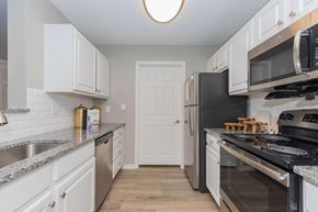 Presto apartment for rent - A kitchen with white cabinets and black appliances.