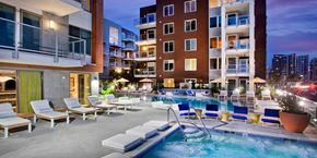 San Diego apartment for rent - A large outdoor pool with lounge chairs and a hot tub in front of apartment buildings.