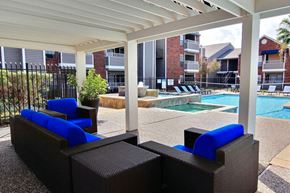 Corpus Christi apartment for rent - A pool area with a white canopy and blue cushioned seating.