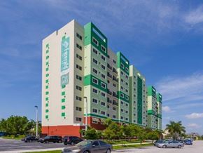 Miami apartment for rent - a tall building with cars parked in front of it