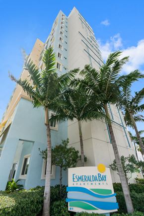 Miami apartment for rent - a tall building with palm trees in front of it