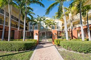 Miami apartment for rent - a fenced in area with palm trees in front of a building