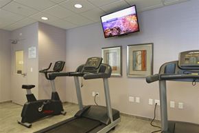 Miami apartment for rent - a gym with exercise machines and a tv on the wall