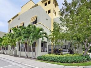 Miami apartment for rent - a white building with palm trees in front of it