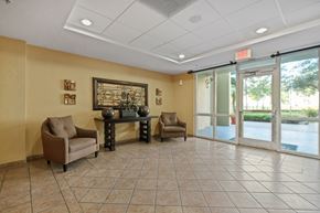 Miami apartment for rent - a lobby with chairs and a table in front of glass doors