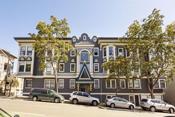 San Francisco apartment for rent - A grey building with a blue trim and a tree in front of it.
