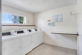Downey apartment for rent - a washer and dryer room with white appliances and a window