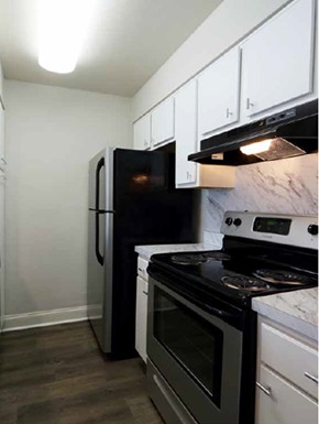 Metairie townhouse for rent - a kitchen with a stove refrigerator and white cabinets