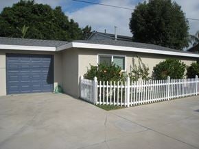 Newport Beach apartment for rent - a white picket fence in front of a house with a blue garage door
