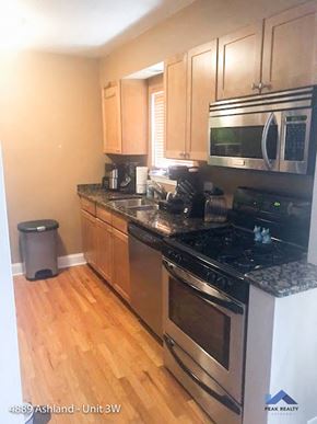 Chicago apartment for rent - a kitchen with stainless steel appliances and wooden floors