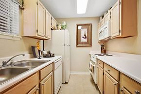 Metairie apartment for rent - A kitchen with wooden cabinets and a white refrigerator.