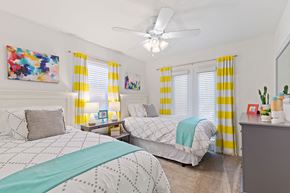 Metairie apartment for rent - A bedroom with two beds, one with a blue blanket, and a ceiling fan.