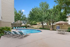 Metairie apartment for rent - A pool surrounded by lawn chairs and trees.