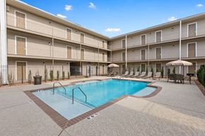 Metairie apartment for rent - A swimming pool in a courtyard surrounded by apartment buildings.