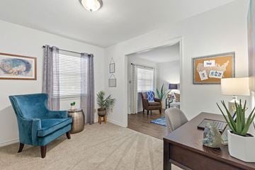 Metairie apartment for rent - A blue chair sits in a living room with a table and a potted plant.