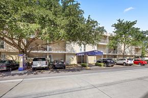 Metairie apartment for rent - A parking lot with cars and a building in the background.