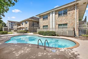 Metairie apartment for rent - A swimming pool in front of a building with a fence around it.