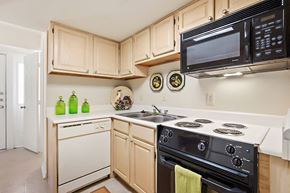 Metairie apartment for rent - A kitchen with a white stove top oven and a black microwave.