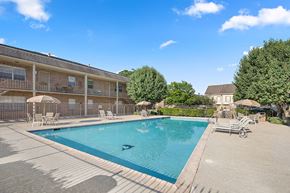Metairie apartment for rent - A large swimming pool is surrounded by lounge chairs and umbrellas.