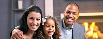 Fort Lee apartment for rent - A family of three is smiling and posing together in front of a fireplace.