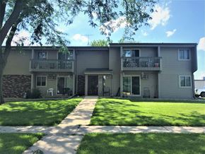 Waunakee apartment for rent - A sunny day at the apartment complex with green lawns and trees.