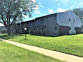 Waunakee apartment for rent - A building with a grey facade and a tree in front of it.