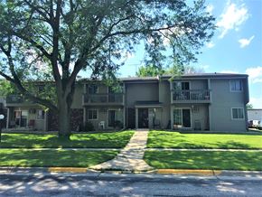 Waunakee apartment for rent - A tree in front of a building with a clear blue sky.