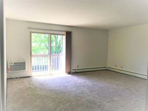 Waunakee apartment for rent - A room with a carpeted floor and a sliding glass door leading to a balcony.