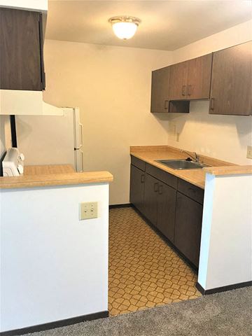 Waunakee apartment for rent - A kitchen with brown cabinets and a white counter.