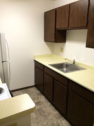 Lodi apartment for rent - A kitchen with brown cabinets and a white fridge.
