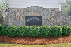 Calhoun apartment for rent - A stone wall with a sign that says Meadowbrook in front of a house.