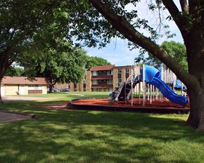 Mankato apartment for rent - a playground with a blue slide in front of an apartment building