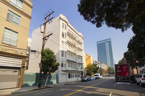 San Francisco apartment for rent - A city street with cars parked on the side and a tall building in the background.
