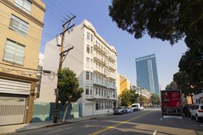 San Francisco apartment for rent - A city street with cars parked on the side and a tall building in the background.