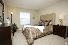 College Park apartment for rent - A bedroom with a large bed and a window with blinds.