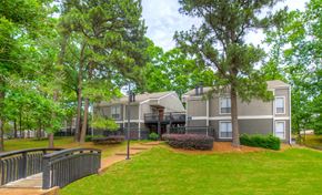 Memphis apartment for rent - A grey building with a black fence and a tree in front.