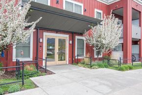 Missoula apartment for rent - the front entrance of a red building with a sidewalk and trees