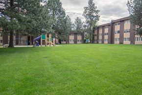 Missoula apartment for rent - a large lawn with a playground in front of an apartment building